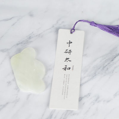Un outil de massage irrégulier en jade vert, conçu de façon ergonomique pour le corps et le visage.
