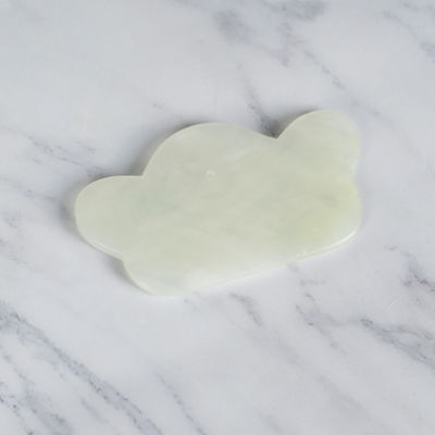 Un outil de massage irrégulier en jade vert, conçu de façon ergonomique pour le corps et le visage.